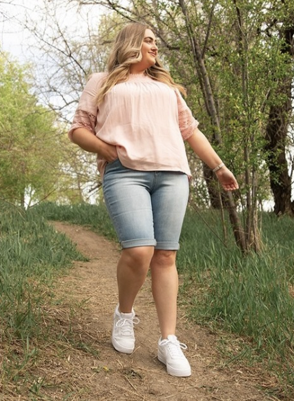 Woman walking through an outdoor trail wearing shorts and a shirt