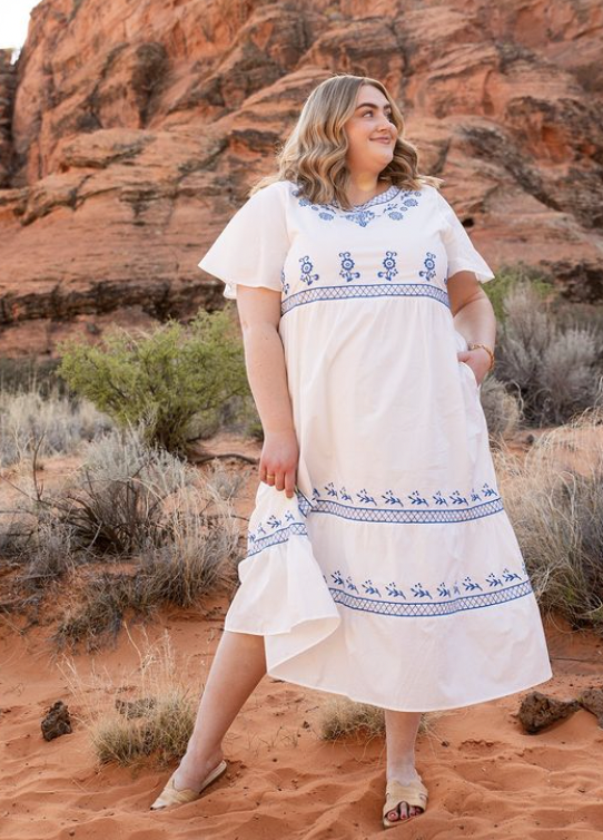 Woman outside in red rocks wearing a white summer dress