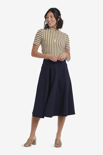 Woman wearing a navy blue midi skirt with a striped top and brown heels