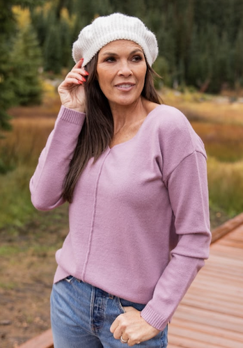 Woman wearing a mauve sweater and white beanie