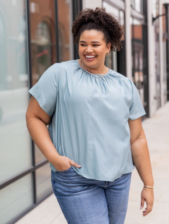 Close up of a woman outside a store wearing jeans and a short sleeve shirt