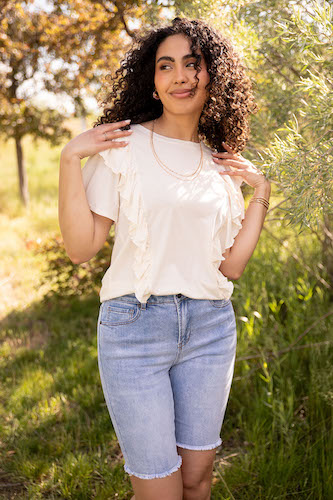 Woman outdoors wearing a white blouse and knee length shorts