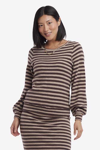 A woman wearing a matching striped sweater and skirt set