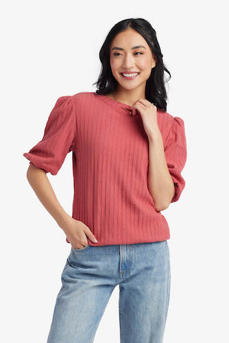 Woman wearing light wash jeans and a rose pink puff sleeve top