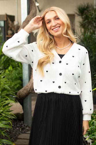 Blonde woman smiling and wearing a white cardigan