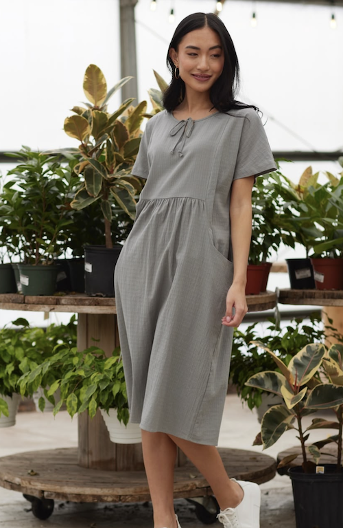 Woman wearing a neutral modest dress in a greenhouse