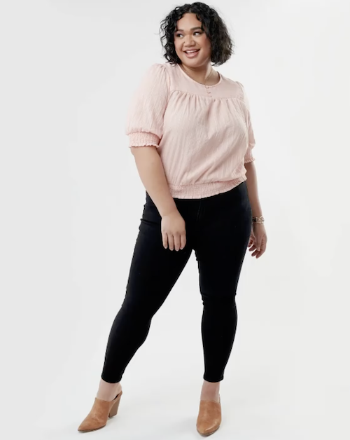 Woman wearing black jeans, a pink top and brown heels