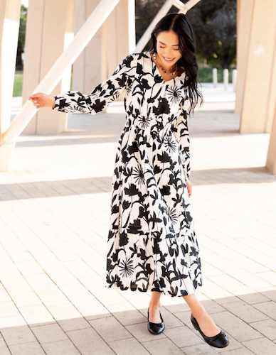 Woman walking wearing a white and black floral maxi dress