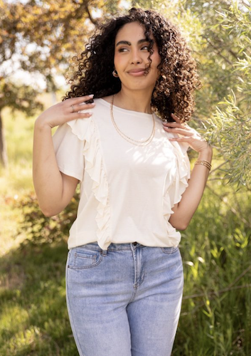 Woman outdoors wearing a white top and bermuda shorts