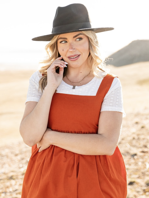 Woman in a rust orange overall and hat in the desert